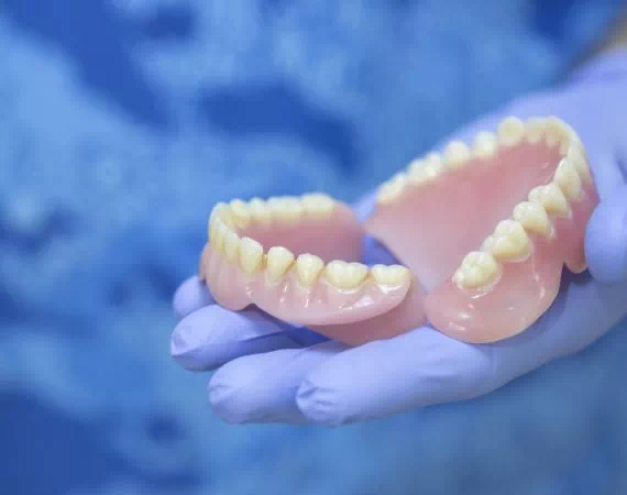 czlowiek trzymający proteze zębową